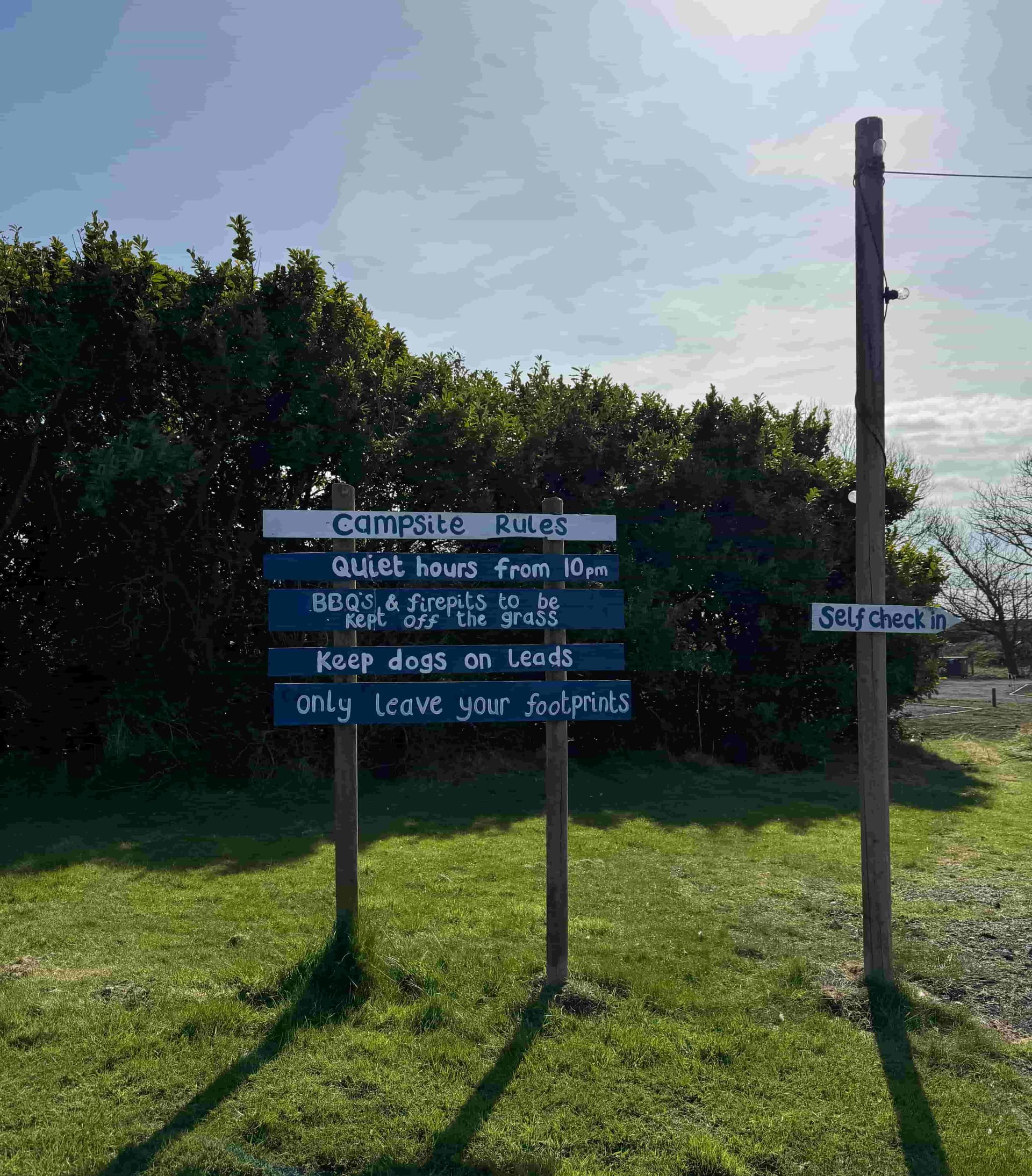 The Coast and Castles campsite rules sign — quiet hours from 10pm, dogs on leads, only leave your footprints