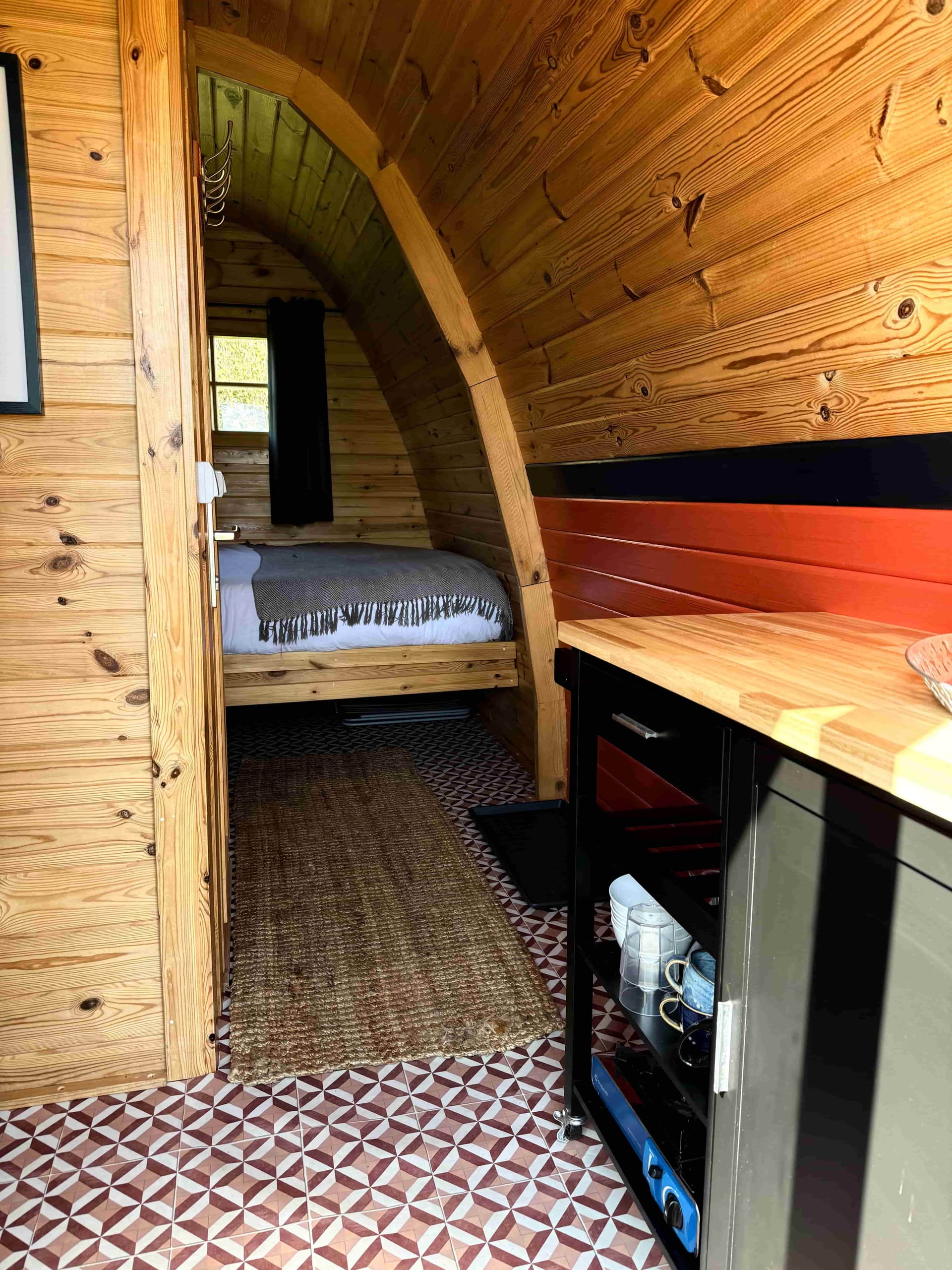 Inside a glamping pod at Coast and Castles showing the kitchenette, patterned tiles and sleeping area